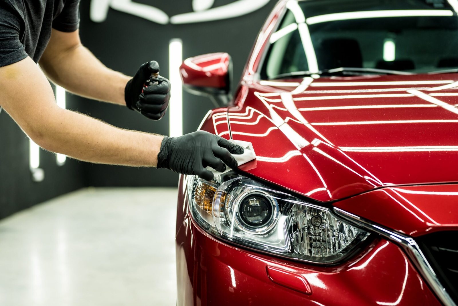 Aplicador passando vitrificação na pintura de um carro vermelho